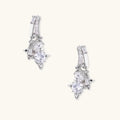 White gold-plated huggie earrings with geometric emerald-cut zirconia clusters in starburst formation on beige background